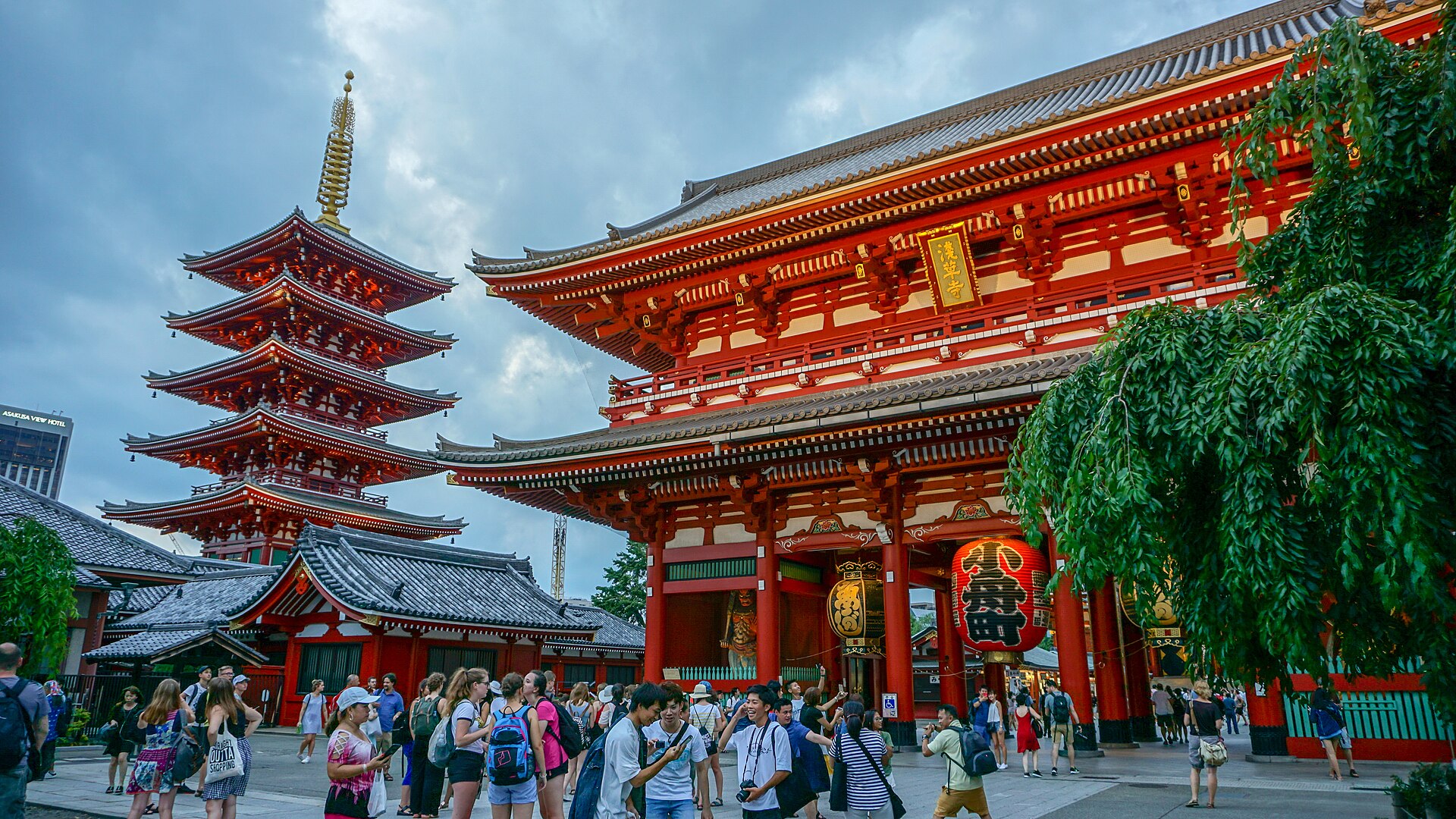 曇り空の下、朱塗りの宝蔵門の大提灯と、左に立つ五重塔を見上げる浅草寺の境内