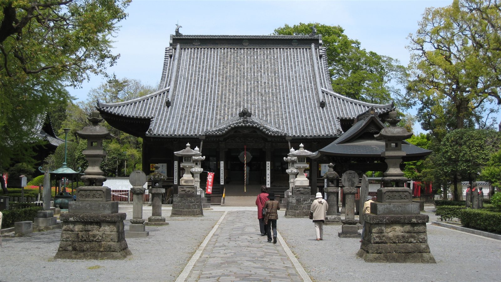 石灯籠が並ぶ参道の先に建つ、大きな瓦屋根の鑁阿寺の本堂