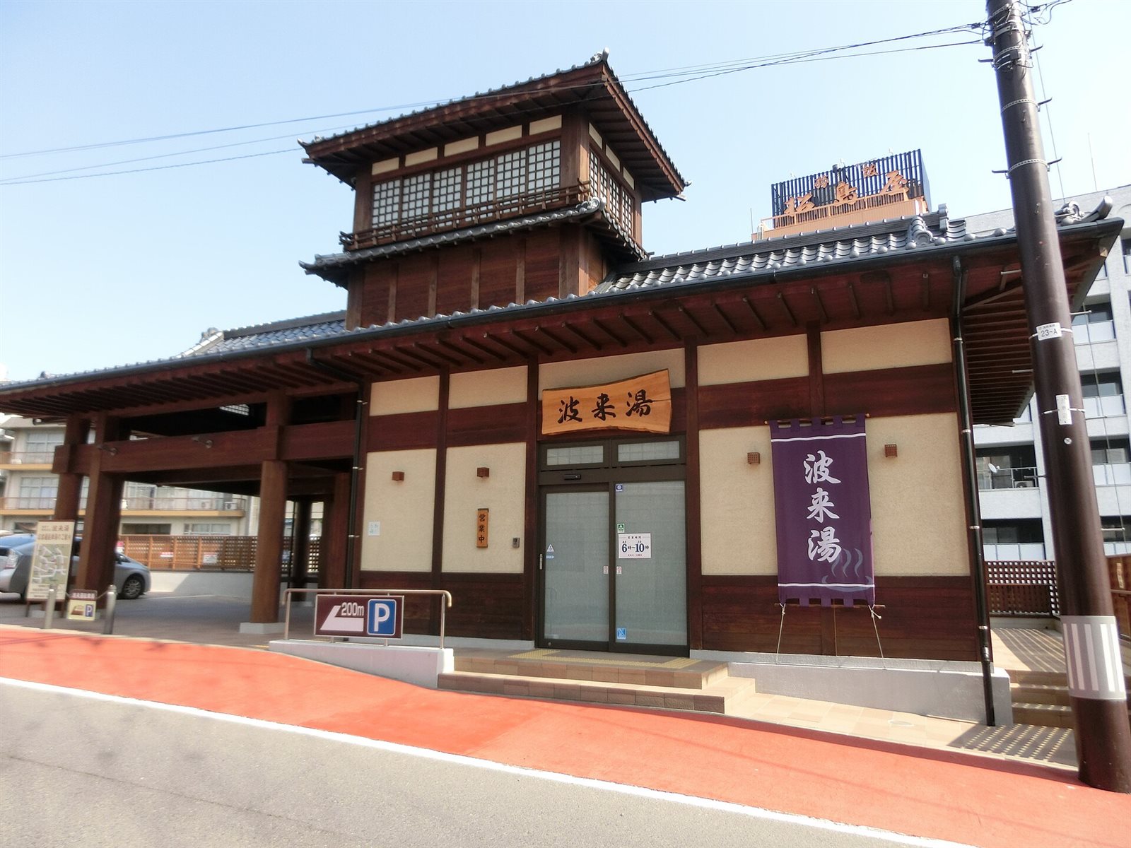 紫ののれんと木の看板がかかる、塔のある屋根を載せた波来湯の建物