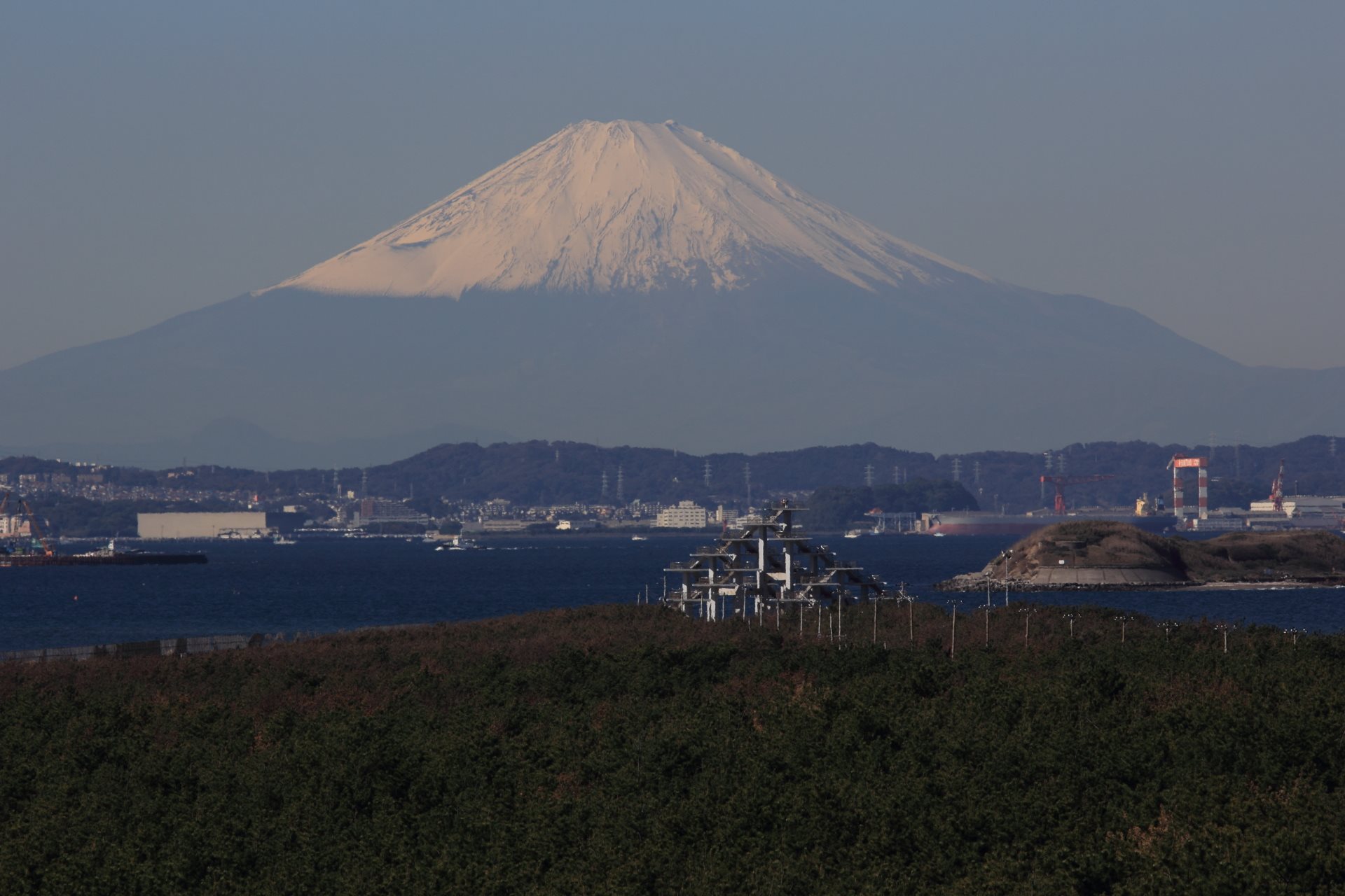 富津岬の松林の向こうに明治百年記念展望塔が立ち、東京湾と対岸の街並みの先に雪をかぶった富士山がそびえている