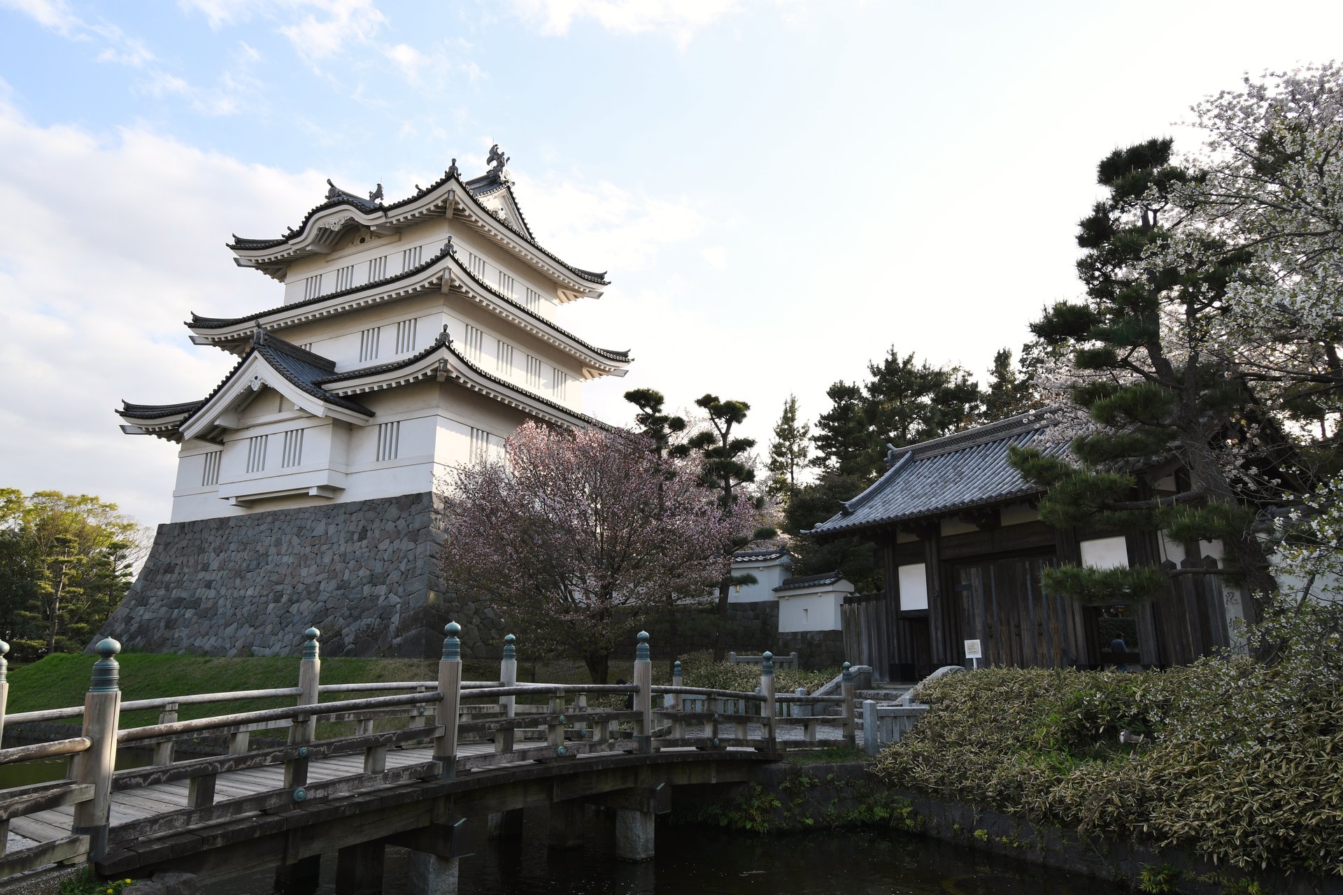 堀の橋の向こうに、白い御三階櫓と城門が見える忍城