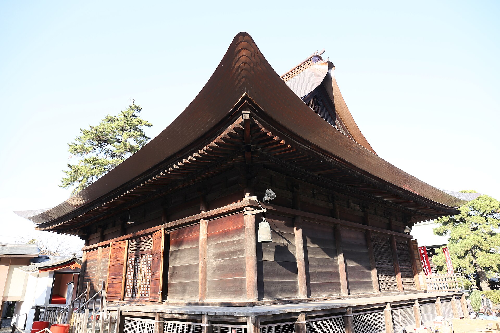 反りのある茶色の大きな屋根をのせた、木造の不動堂を横から見た様子