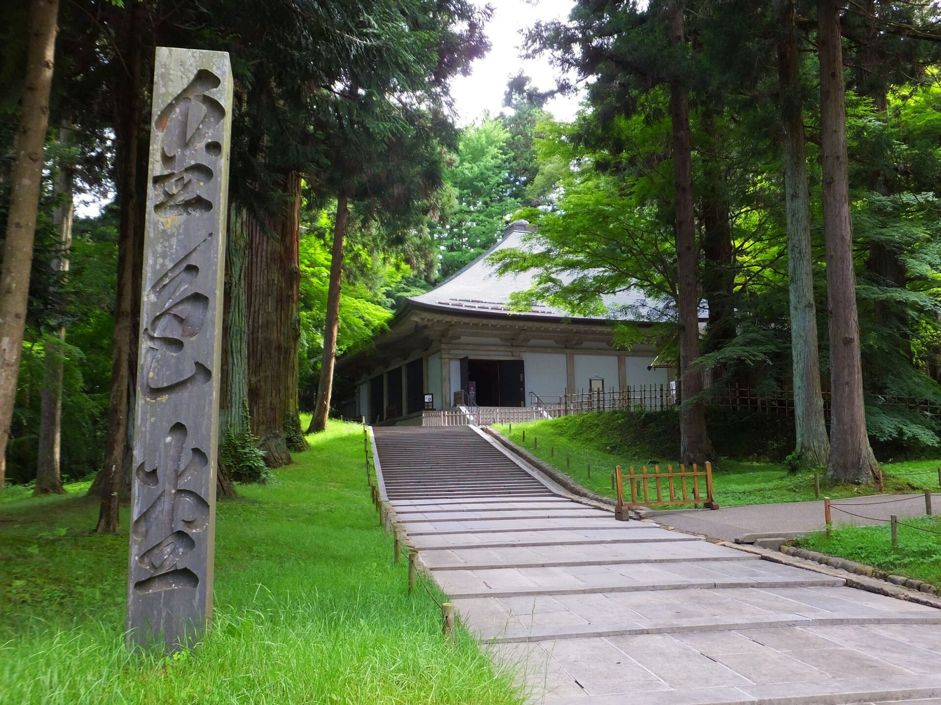 杉木立の中に、金色堂の標柱と、金色堂を覆う建物が見える中尊寺の境内