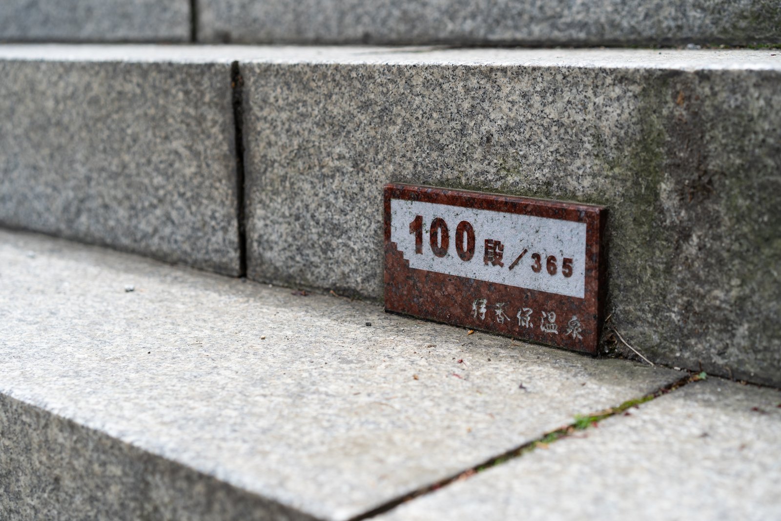 石段の側面にはめ込まれた石のプレート。「100段／365」「伊香保温泉」と刻まれている