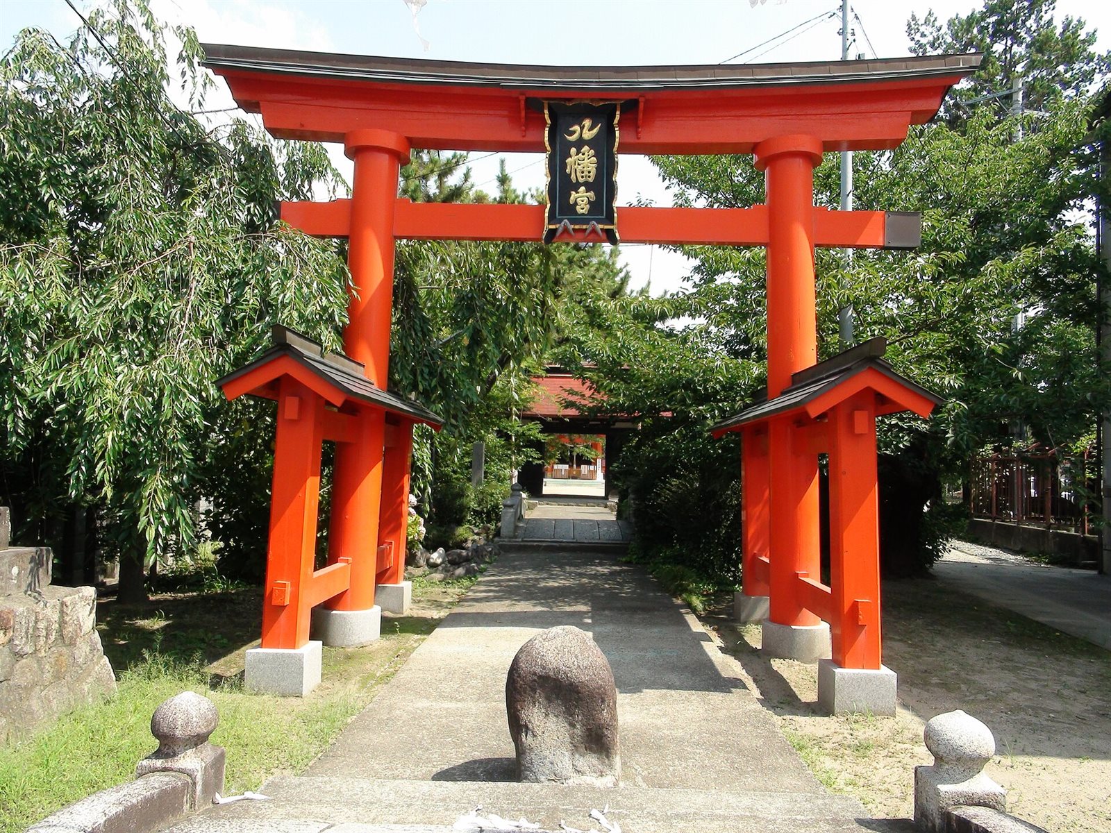 石和八幡神社の朱色の鳥居。額の「八幡宮」の「八」が鶴の形で書かれ、奥に参道と社殿の門が見える