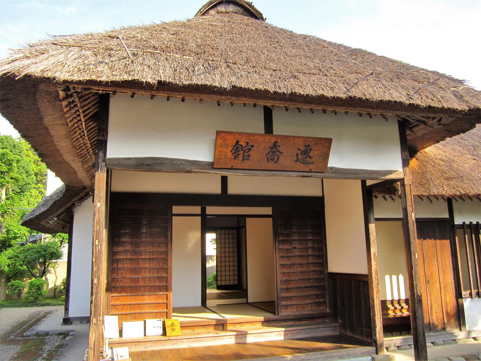 大きな茅葺屋根の下、「遷喬館」の木の扁額が掛かる玄関