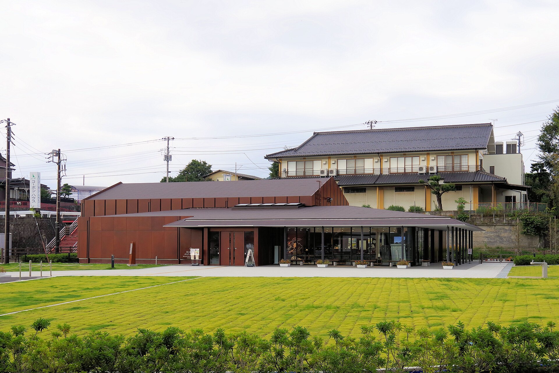 芝生の向こうに、赤茶色の外壁の低い建物が建つ韮山反射炉ガイダンスセンター