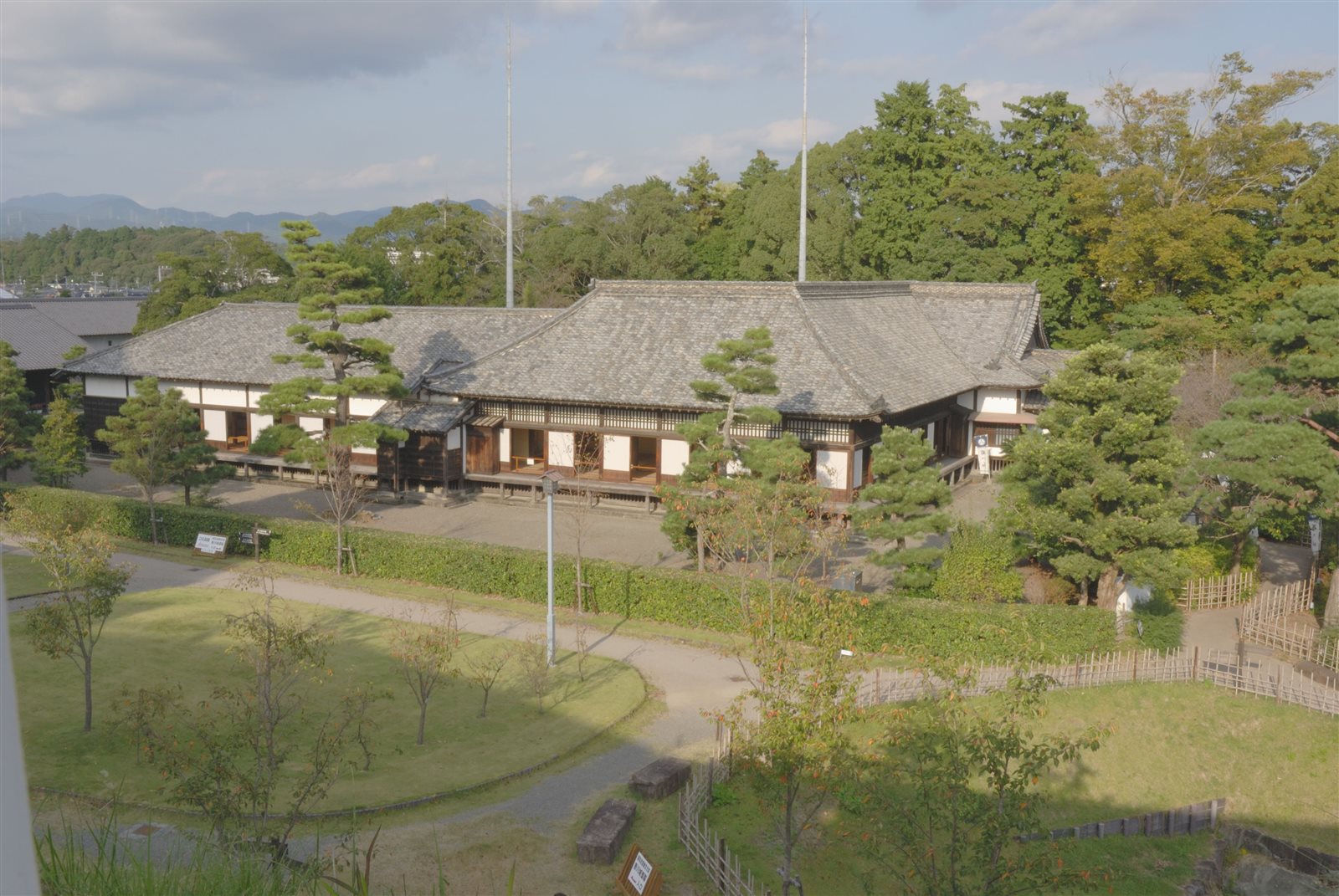 松の木と芝生の庭の向こうに、瓦屋根の低い平屋が横に広がる掛川城の御殿