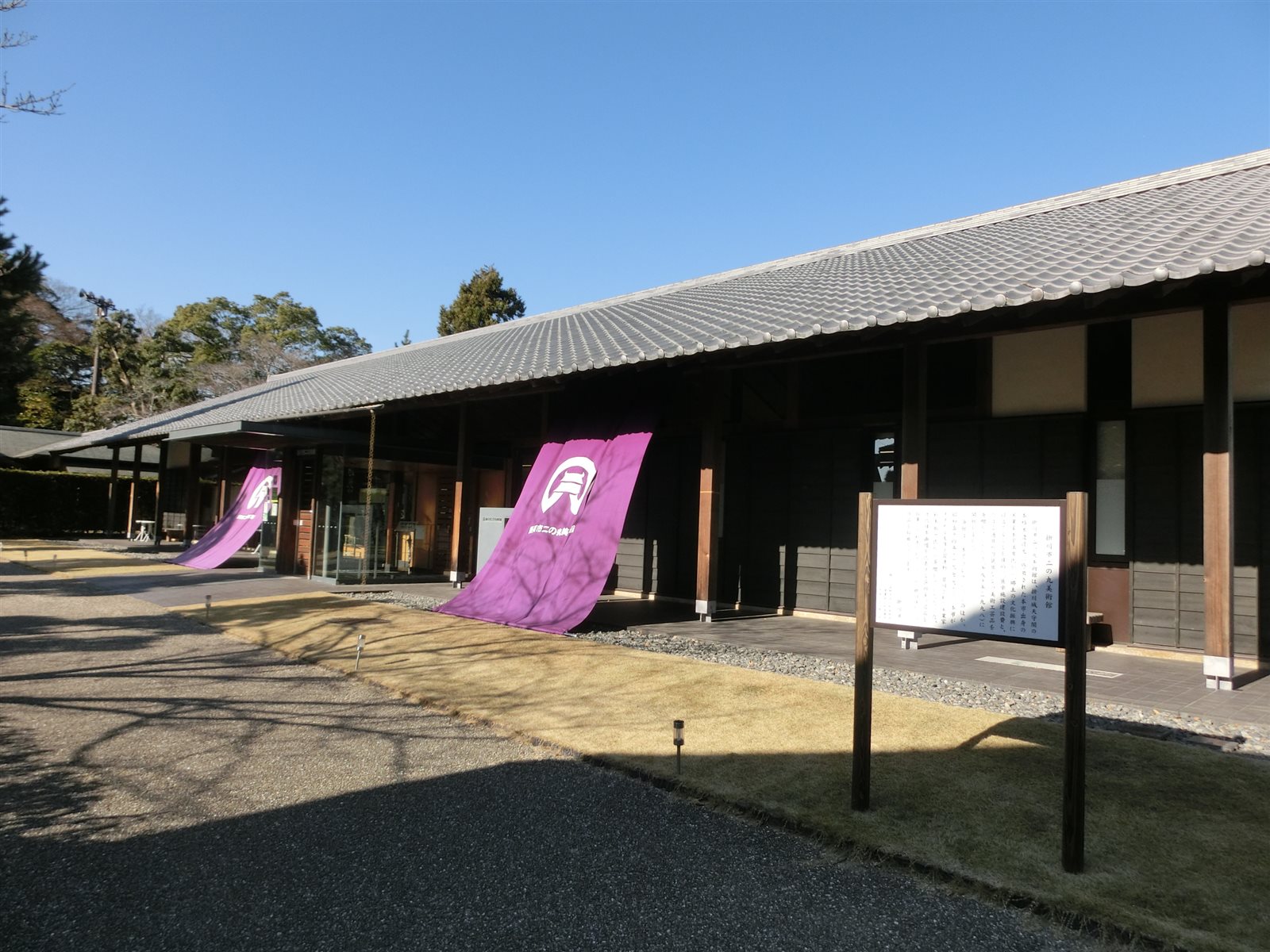 低い瓦屋根の下に、紫の大きな幟が垂れる二の丸美術館の入口