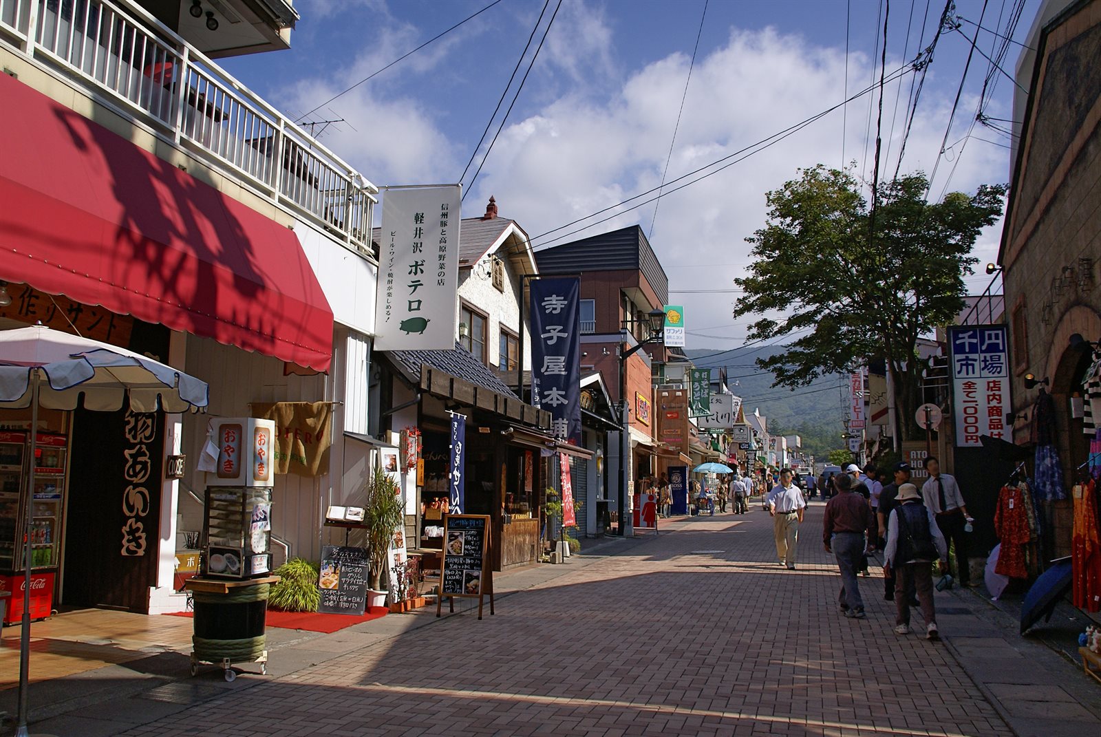 れんが敷きの通りの両側に商店が並び、奥に山が見える旧軽井沢銀座通り