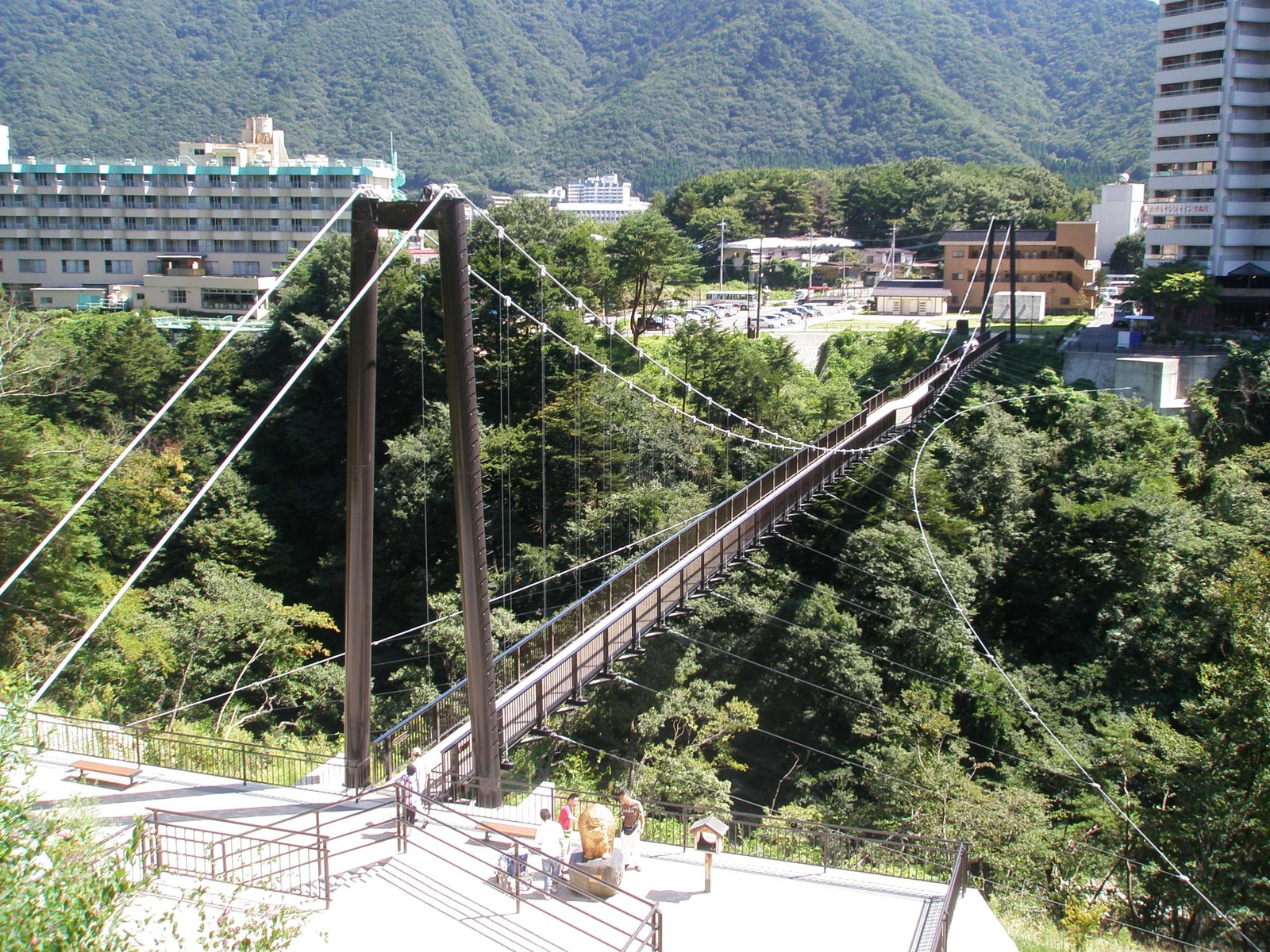 深い谷に架かる吊橋と、その向こうに並ぶ温泉街のホテル