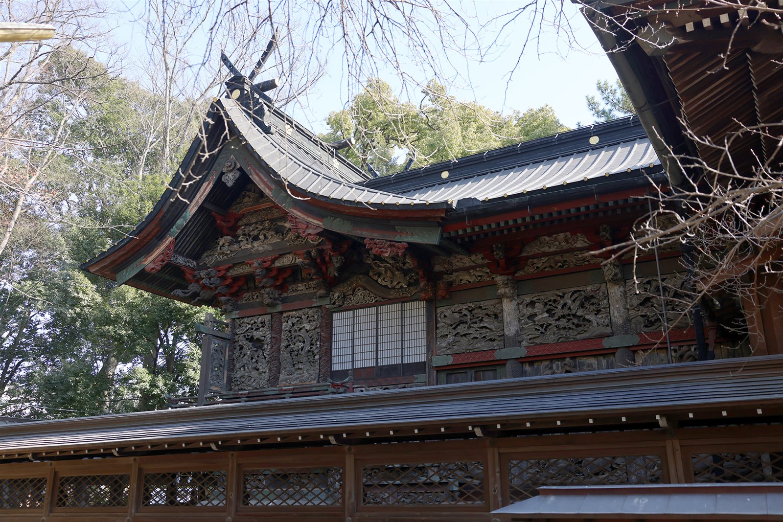 彫刻と赤い飾りが並ぶ、桐生天満宮の本殿・幣殿の屋根と壁