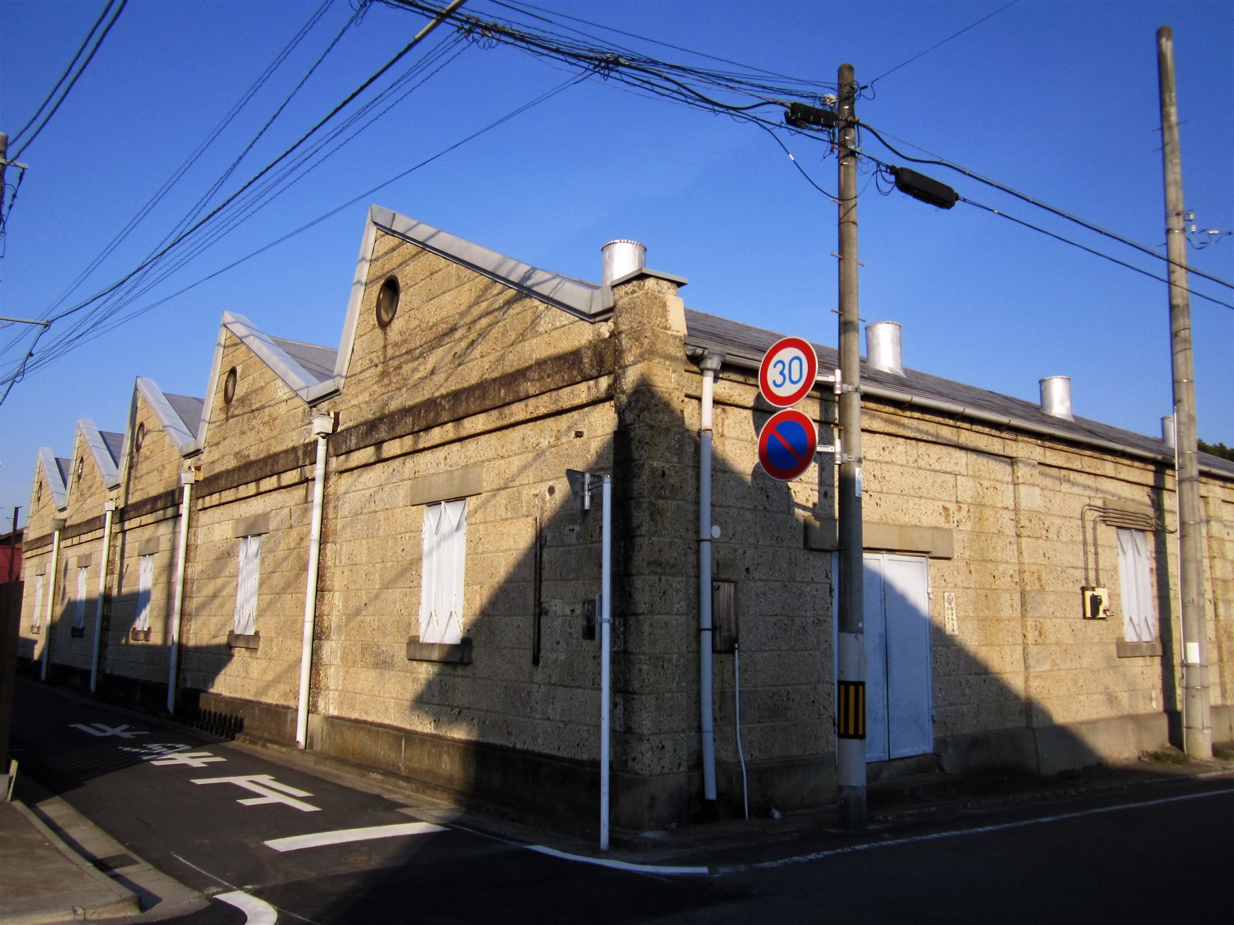 石造りの壁に、のこぎりの歯のように三角の屋根が並ぶ織物工場の建物