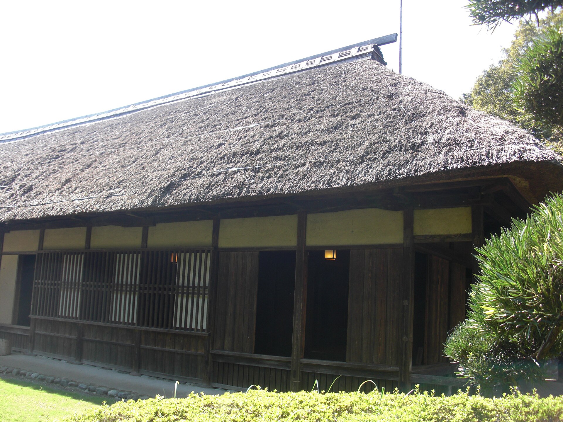 厚い茅ぶきの屋根と、板戸や格子のある旧安西家住宅の正面