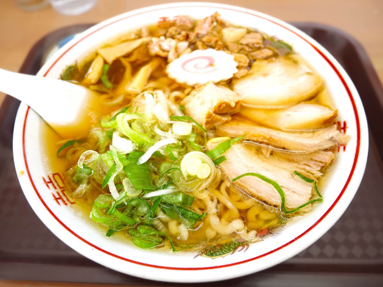 縮れた平打ち麺とチャーシュー、ネギの載った醤油味のラーメン