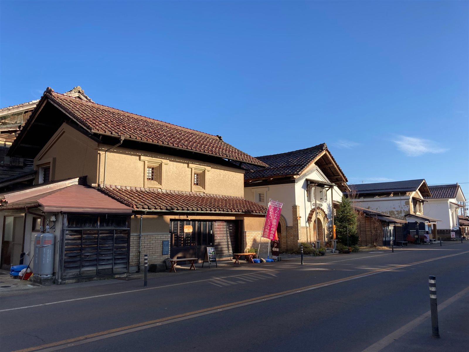 白壁と瓦屋根の蔵が青空の下に並ぶ、小田付の通り