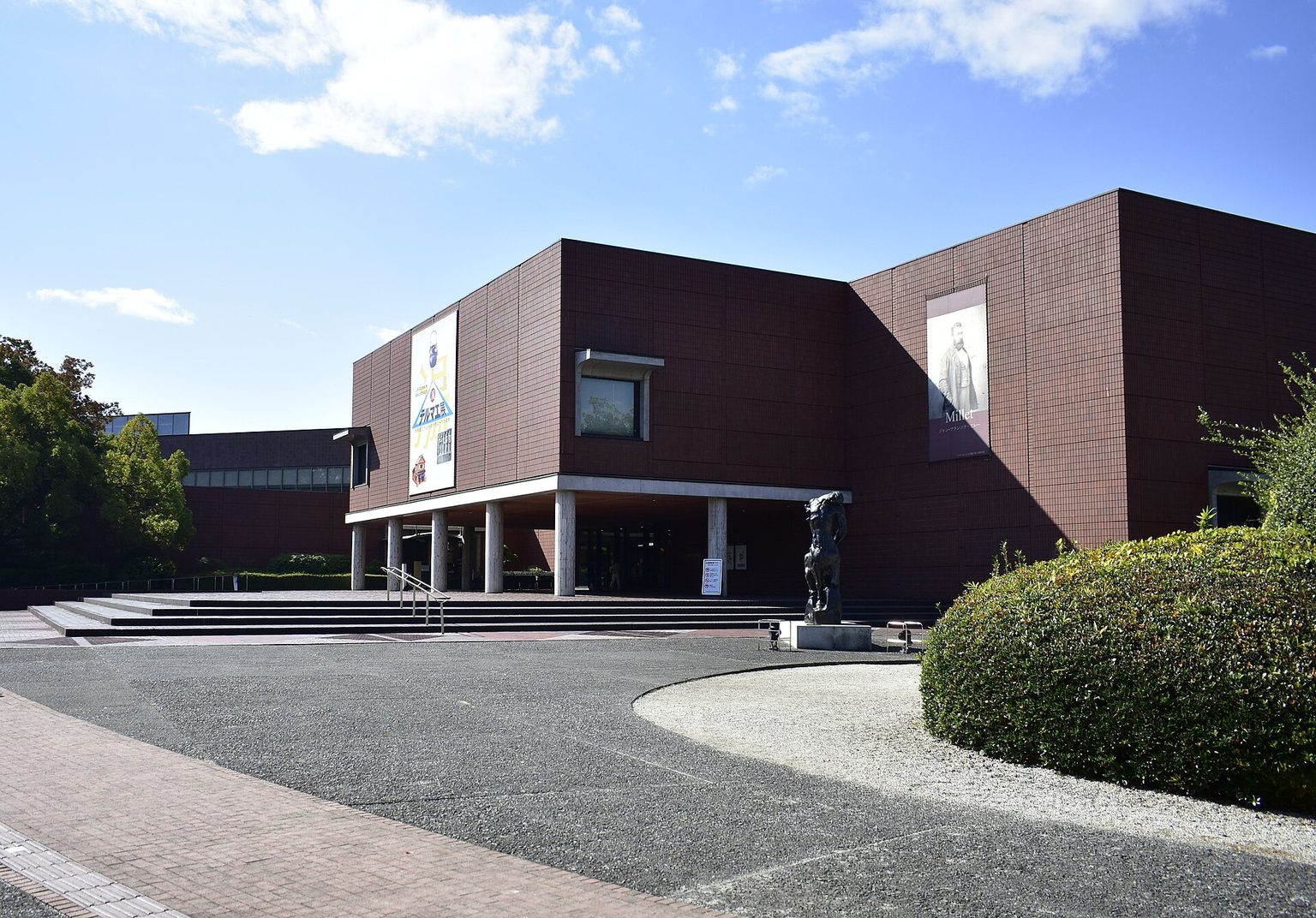 茶色のタイルを張った、山梨県立美術館の建物と前庭