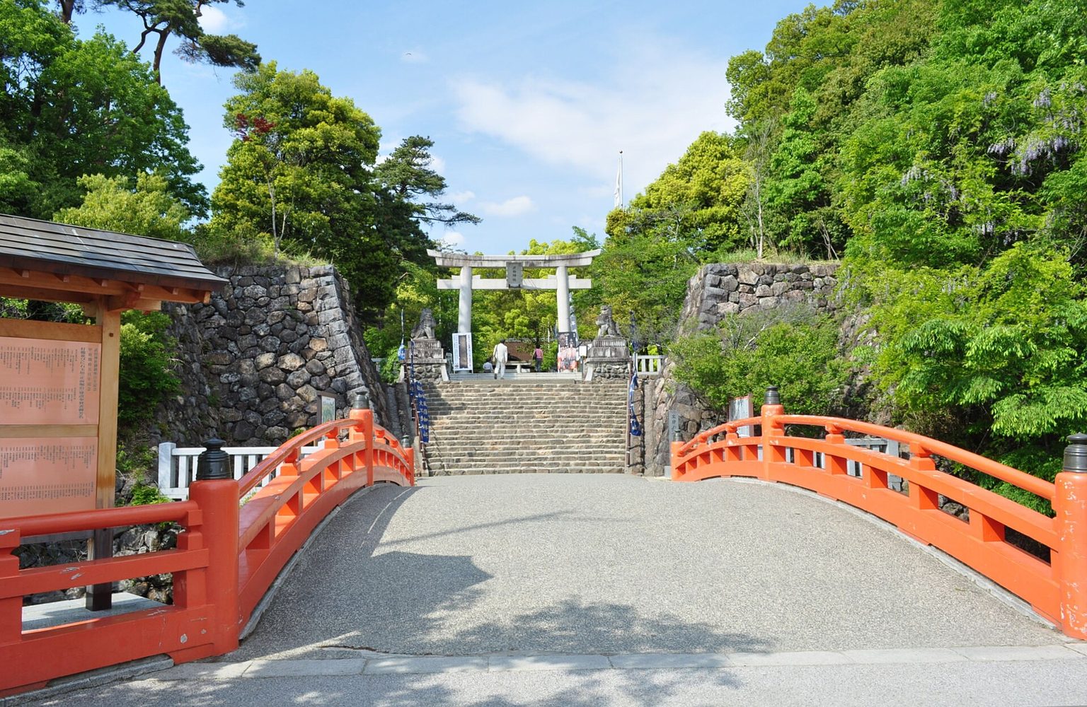 赤い橋の先に石段と鳥居が続く、武田神社の入口