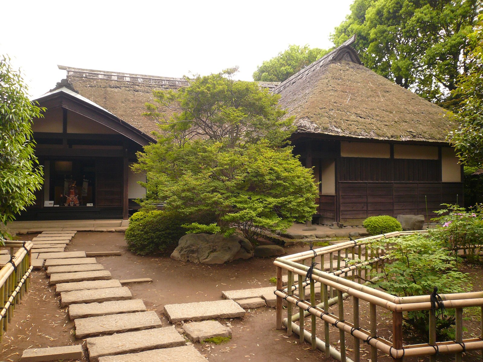 庭の飛び石の先に、茅葺き屋根の座敷が建つ鷹見泉石記念館