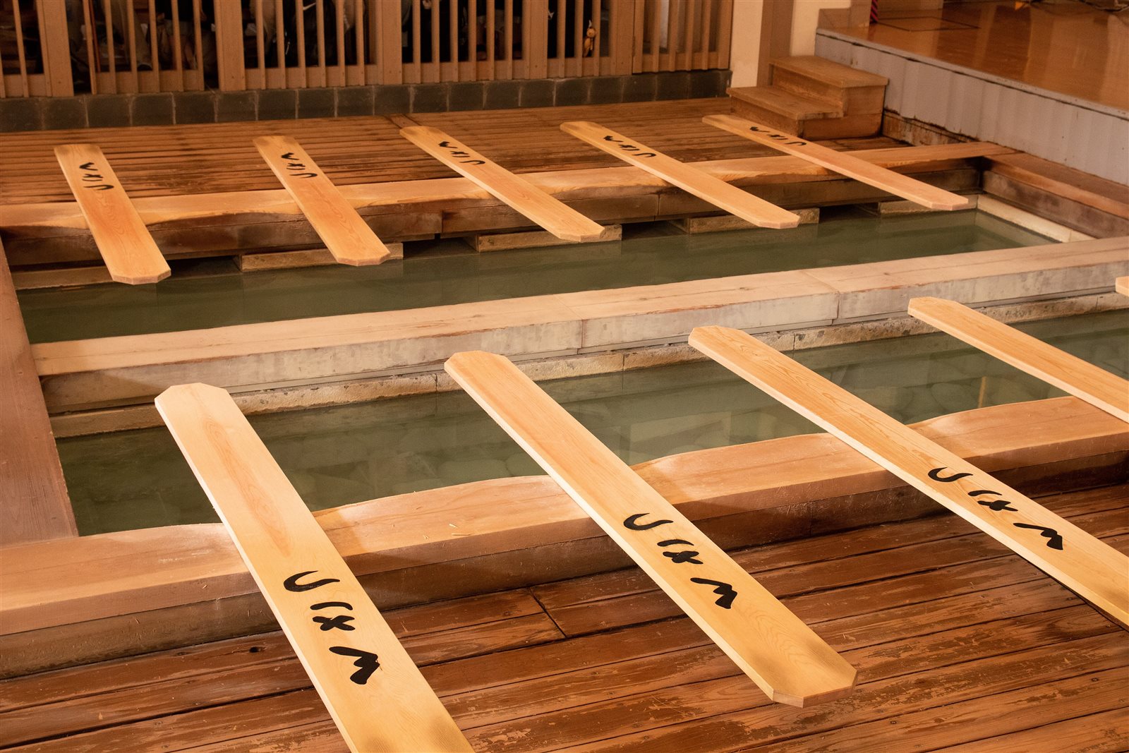熱乃湯の湯船の縁に並べて置かれた、文字の書かれた湯もみ板