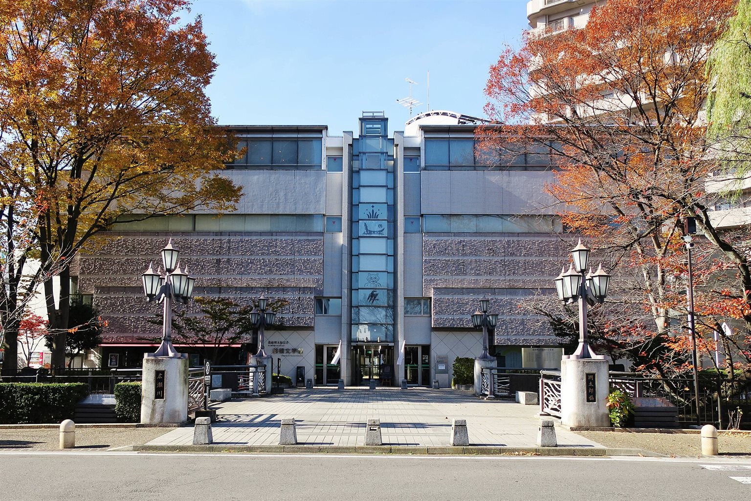 紅葉した木々の間に、灯籠形の街灯が並ぶ前橋文学館の正面入口