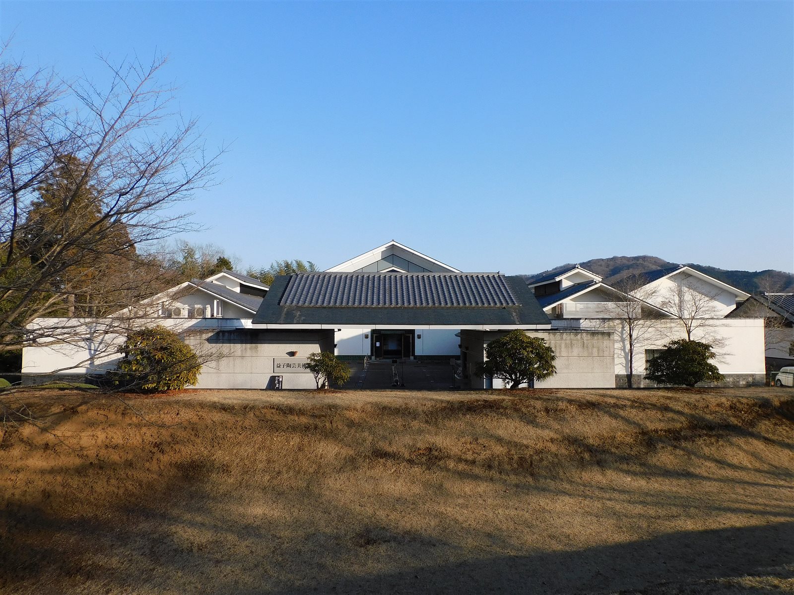 冬の晴れた空の下、低い瓦屋根と白い壁の建物が並ぶ益子陶芸美術館