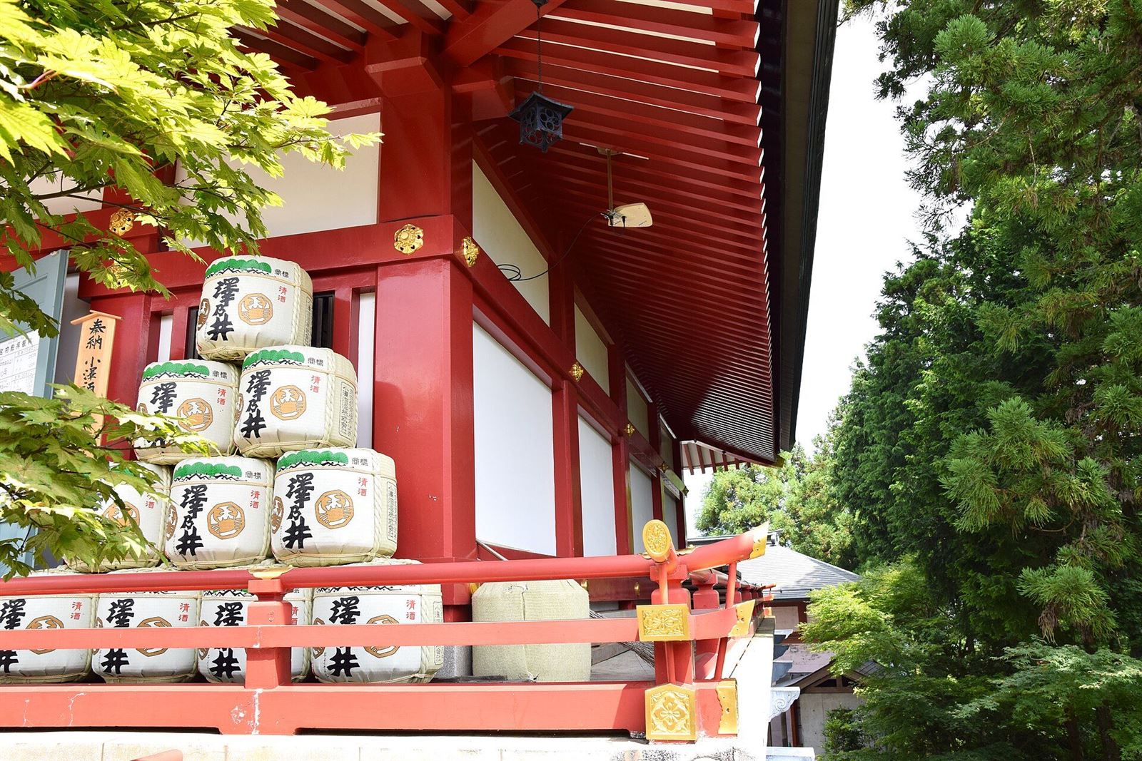 朱塗りの社殿の縁に、奉納された酒樽が積まれた武蔵御嶽神社の境内