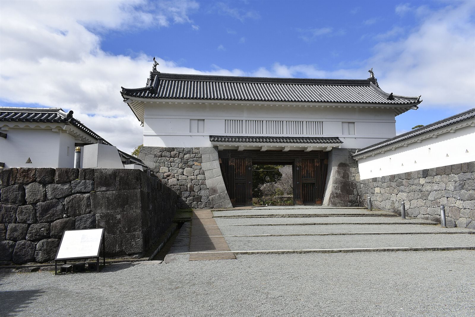 小田原城の銅門。石垣と白い土塀に囲まれた枡形の奥に、瓦屋根の渡櫓門が建ち、木の扉が開いている