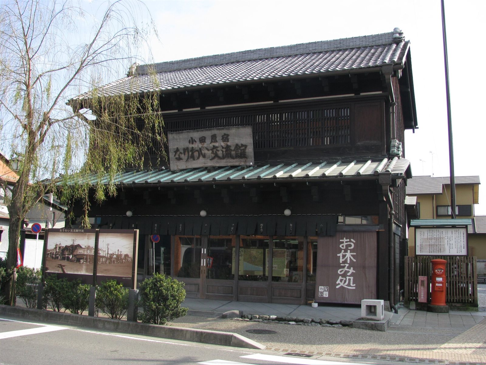 小田原宿なりわい交流館の外観。木造2階建ての町家で、2階正面に格子と「小田原宿 なりわい交流館」の看板、1階に「お休み処」ののれんが掛かっている