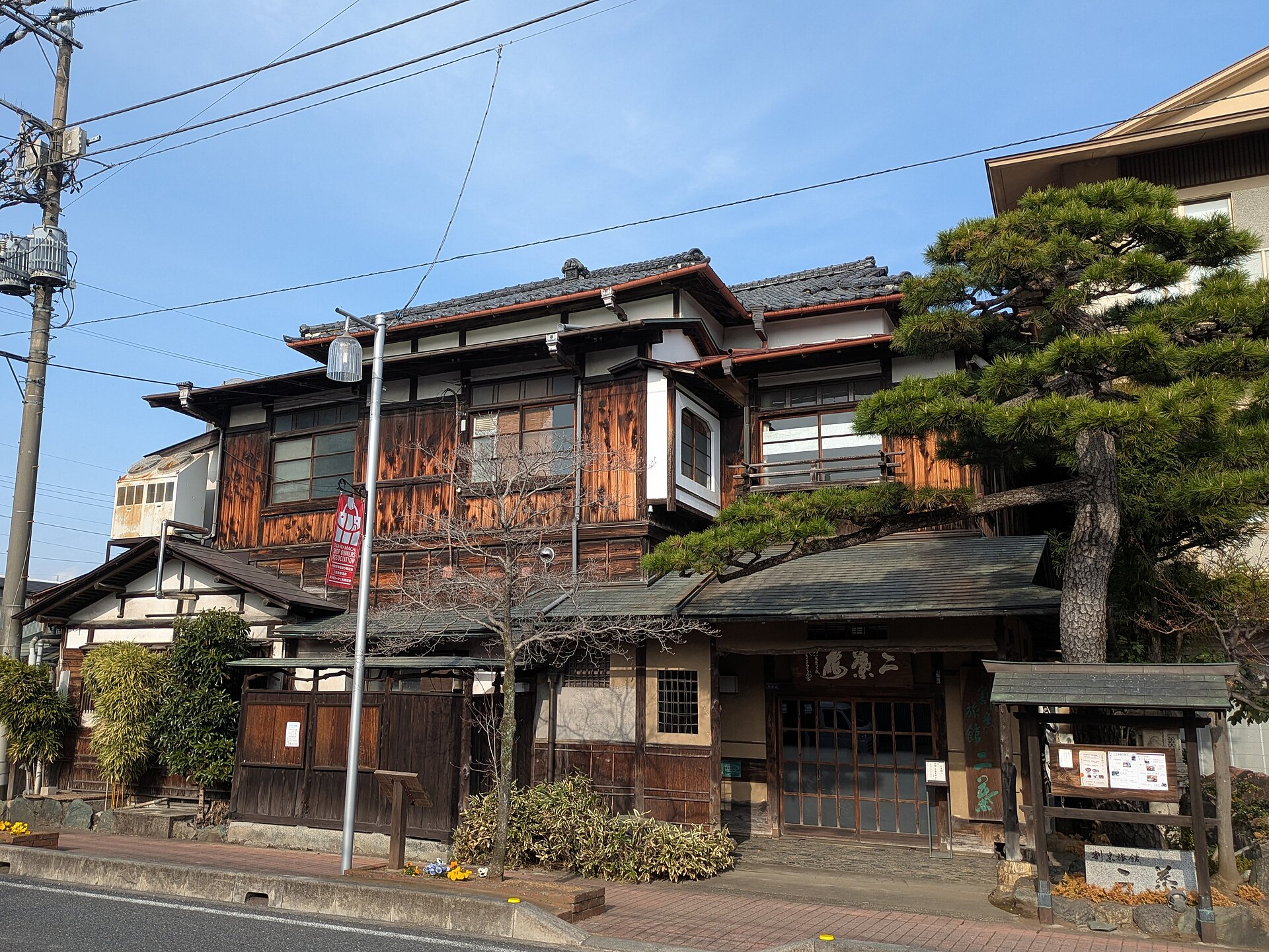 松の木の脇に立つ、古い木造二階建ての割烹旅館の建物