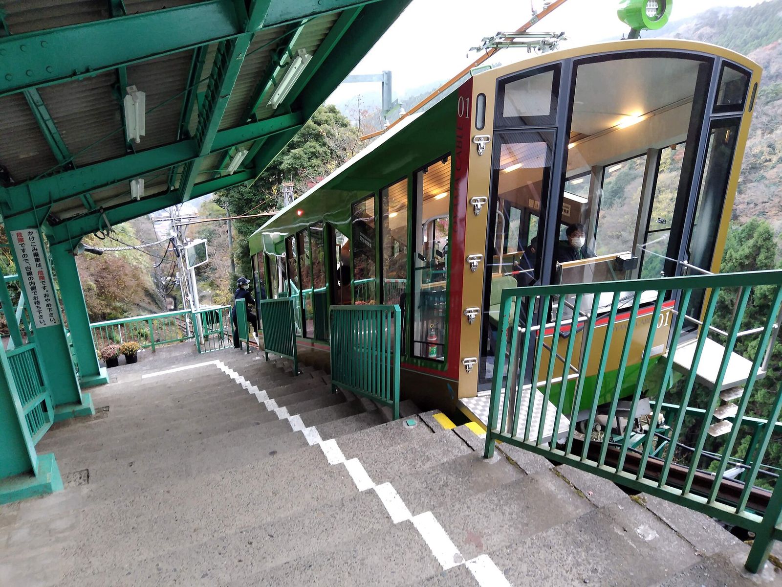 緑と赤の車体のケーブルカーが停まる、阿夫利神社駅のホーム