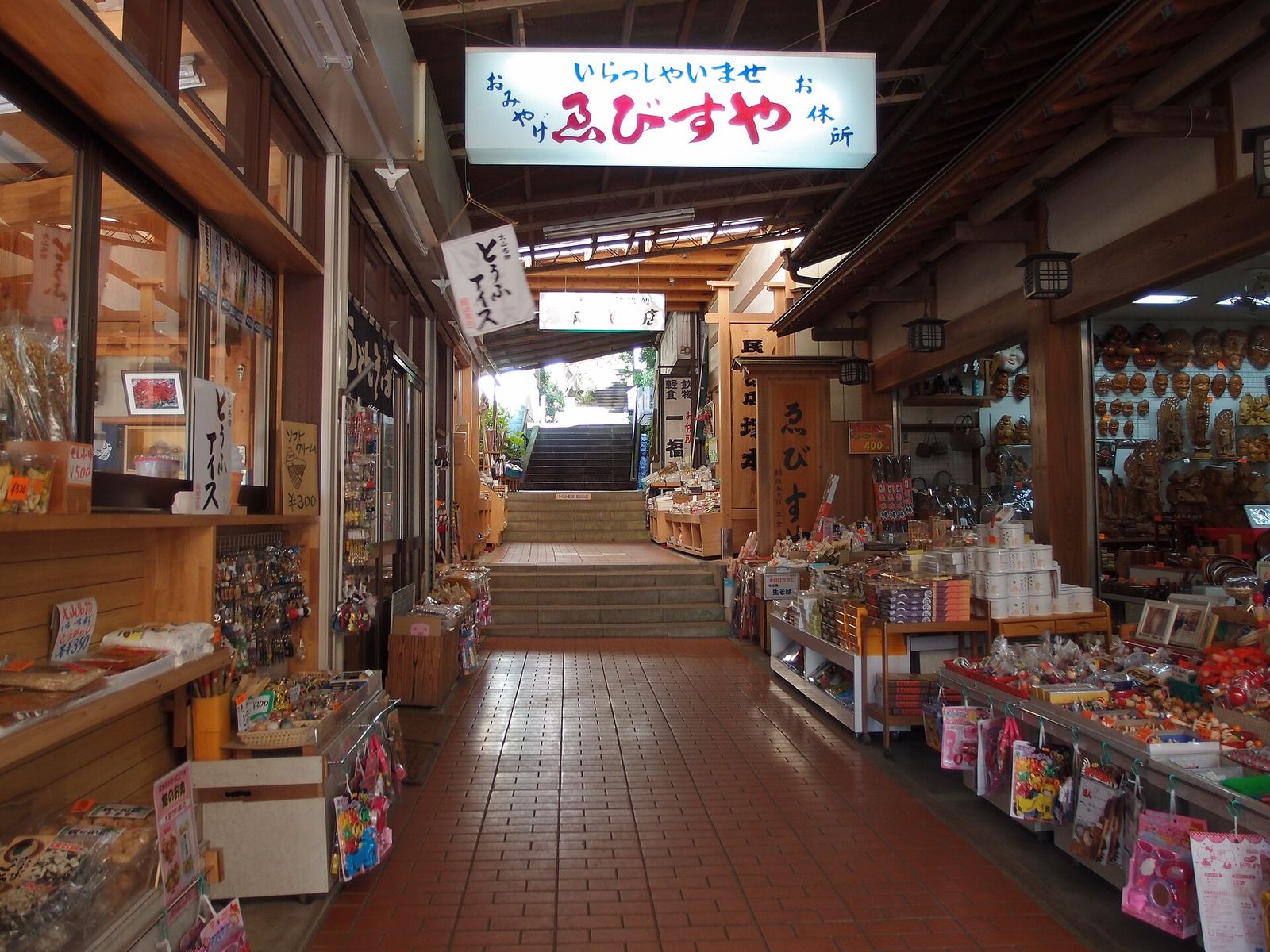 土産物の店が両側に並ぶ、屋根のあるこま参道と奥へ続く階段