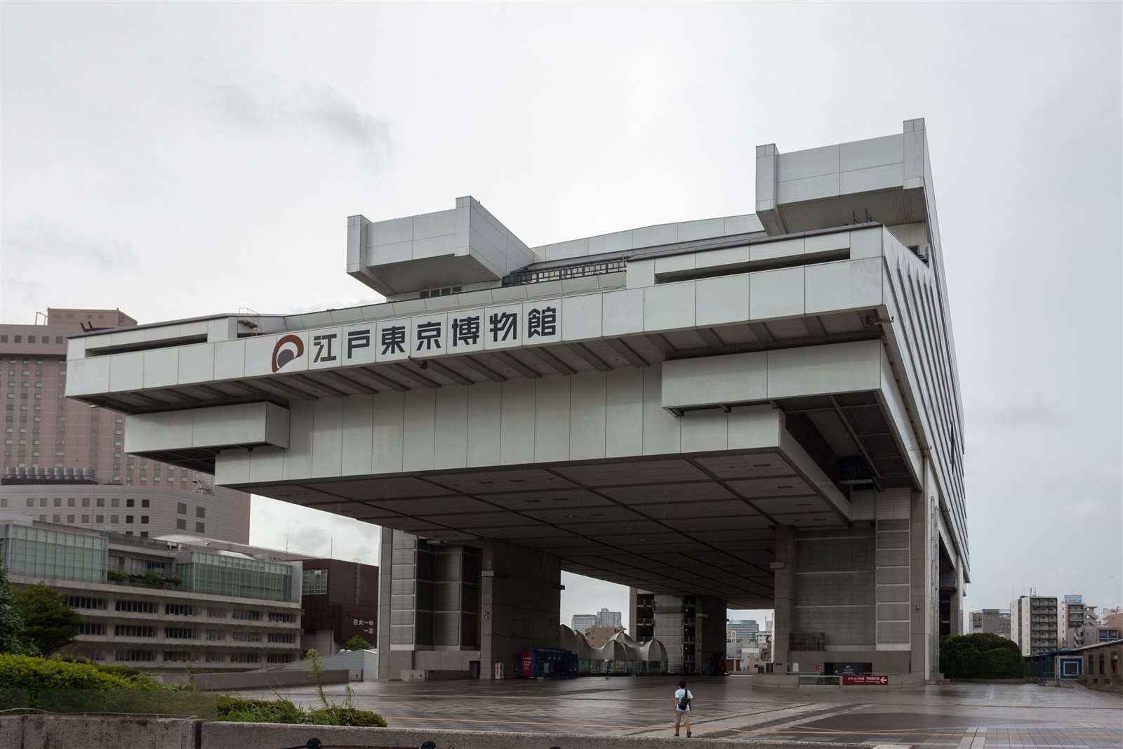 曇り空の下、高い脚の上に大きな箱型の展示棟が張り出す江戸東京博物館の外観