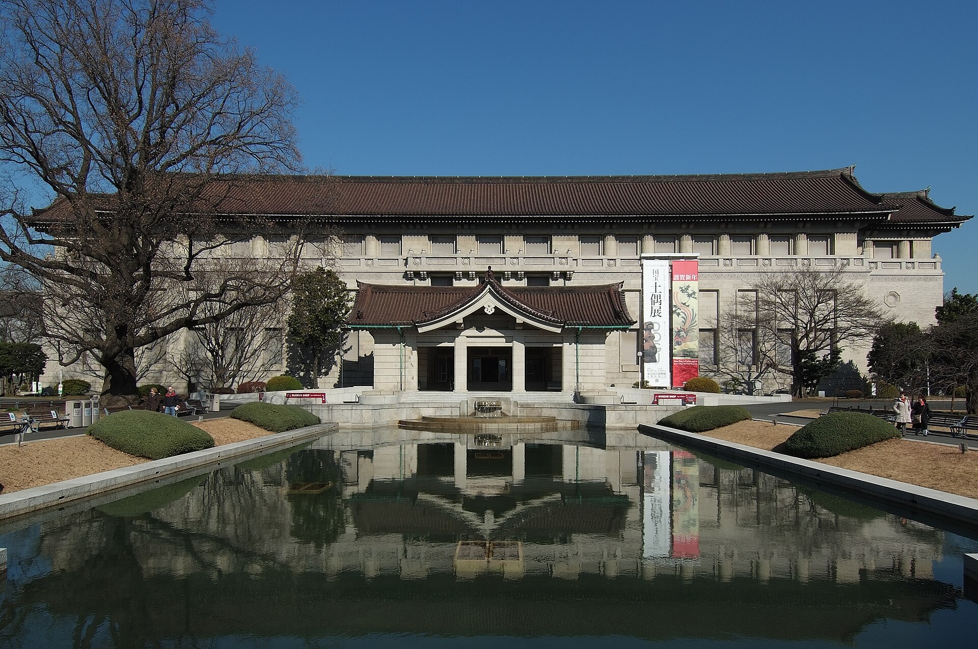 青空の下、池に姿を映す、瓦屋根の東京国立博物館の本館