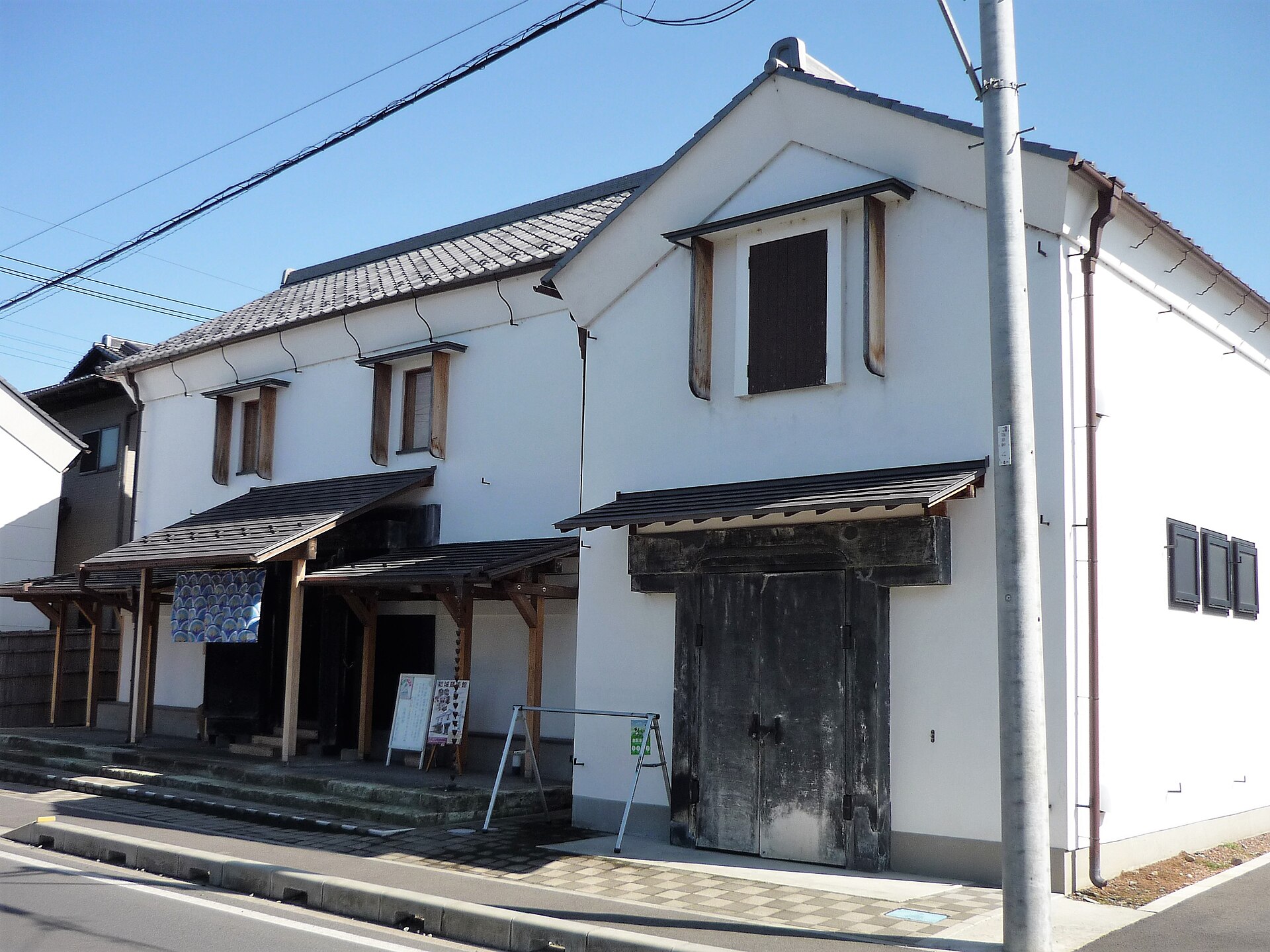白壁の蔵造りの建物と、木の庇がかかる結城蔵美館の入り口